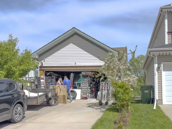 Calgary, Alberta, Kanada. 27 Mayıs 2025. Komşuların mavi gökyüzünün altında araç gereçlere, bitkilere ve ev eşyalarına göz attığı bir varoş garaj satışı başlıyor..