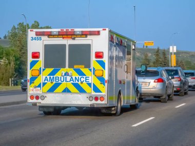 Calgary, Alberta, Kanada. 8 Haziran 2025. Acil durum işaretlerini belirgin bir şekilde gösteren Alberta Sağlık Hizmetleri ambulansının arka tarafında acil yardım ekipleri yer alıyor.