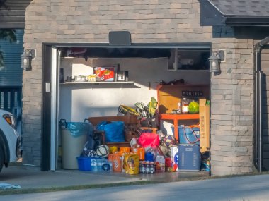 Calgary, Alberta, Kanada. 8 Haziran 2025. Güneşli bir garaj açık duruyor, ev eşyaları, depolama kutuları, organizasyon ihtiyacına dair ipuçları veriyor..