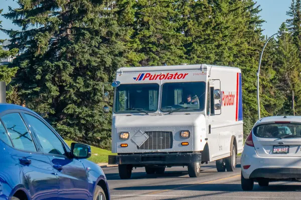 Calgary, Alberta, Kanada. 8 Haziran 2025. Bir Purolator dağıtım kamyonu Calgary 'de ağaçlık bir caddede geziniyor. Etkili paket ve kurye hizmetlerini sembolize ediyor..