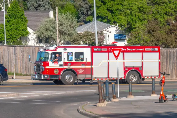 Calgary, Alberta, Kanada. 8 Haziran 2025. Canlı bir Calgary İtfaiyesi kamyonu, özellikle kırmızı ve beyaz, önemli kamu güvenliği hizmetlerini temsil eden bir yerleşim bölgesinden geçiyor..