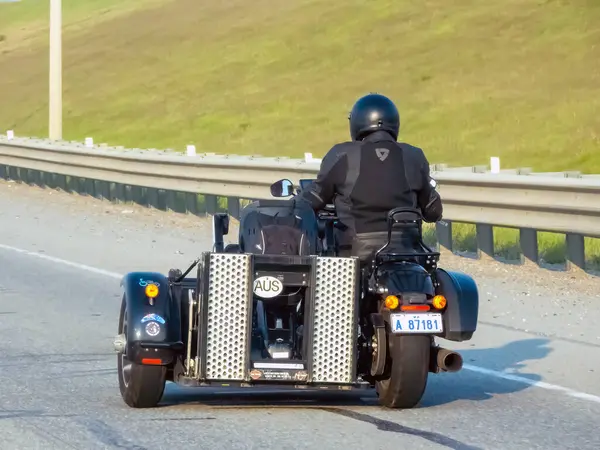 Calgary, Alberta, Kanada. 8 Haziran 2025. Bir motosikletçi kask takıyor ve özel motosiklet sepetli bir motosiklet sürüyor, doğal bir arka plana karşı eşsiz bir yolculuk sergiliyor.. 