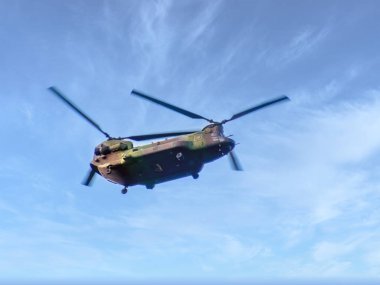 Calgary, Alberta, Kanada. 14 Haziran 2025. Boeing CH-47 Chinook askeri helikopterinin dinamik bir görüntüsü canlı mavi bir gökyüzüne doğru süzülürken ince bulutlar onun güçlü varlığını vurguluyor..