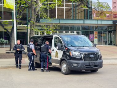 Edmonton, Alberta, Kanada. 12 Haziran 2025. Edmonton Polis Teşkilatı memurları binanın dışında bir polis minibüsünün yanında duruyor. Bu da aktif kolluk kuvvetleri ve toplum varlığı öneriyor..