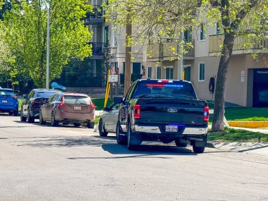 Edmonton, Alberta, Kanada. 12 Haziran 2025. Arka camında belirgin kırmızı, beyaz ve mavi detay taşıyan işaretsiz bir polis Ford pikap diğer araçlarla birlikte bir iskan caddesinde park halinde..