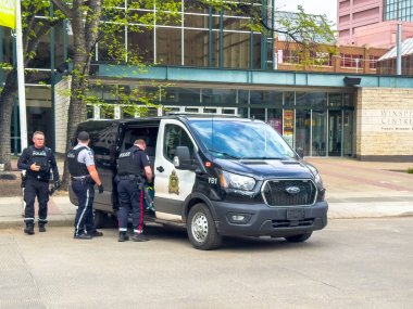 Edmonton, Alberta, Kanada. 12 Haziran 2025. Edmonton Polis Teşkilatı memurları binanın dışında bir polis minibüsünün yanında duruyor. Bu da aktif kolluk kuvvetleri ve toplum varlığı öneriyor..