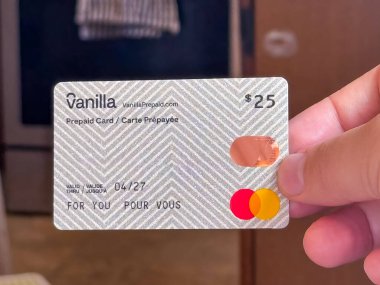 Calgary, Alberta, Kanada. 11 Haziran 2025. Vanilla Prepaid Mastercard 'ı tutan bir el. İçinde 25 dolarlık bir değer ve özel bir sembol var. Hediye ve güvenli işlemler için ideal..