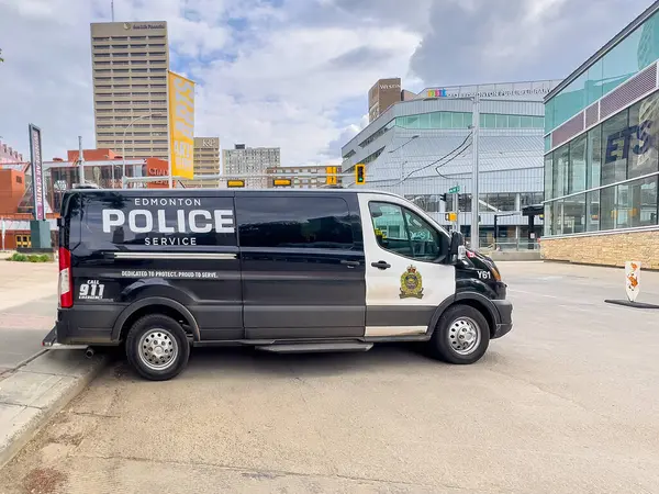 Edmonton, Alberta, Kanada. 12 Haziran 2025. Bir Edmonton Polis Servisi minibüsü şehir binaları ve arka planda bir ETS tabelası olan bir caddede park halinde, tipik bir şehir manzarasını yakalıyor..