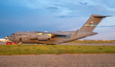 Calgary, Alberta, Kanada. 16 Haziran 2025. Korkunç bir Amerikan Hava Kuvvetleri C-17 Globemaster III, Calgary Uluslararası Havalimanı 'nın pistinde alacakaranlıkta beklemektedir..