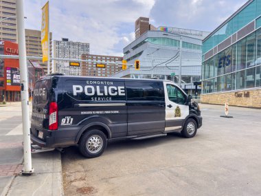 Edmonton, Alberta, Kanada. 17 Haziran 2025. Edmonton Polis Servisi minibüsü belediye binası ve halk kütüphanesinin yakınına park edilmiş, şehir polisliği ve şehir mimarisi sergileniyor..