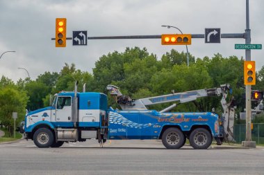 Calgary, Alberta, Kanada. 27 Haziran 2025. Mavi ve beyaz renkli ağır yük taşıyan bir Şehir Çekici, trafik ışıklarının altında yol yardımı ve iyileşmeye hazır bir kavşakta bekliyor.