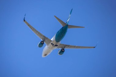 Calgary, Alberta, Kanada. 26 Haziran 2025. Ticari bir Westjet uçağı açık mavi gökyüzünde süzülür, görünürde, hava yolculuğunun özünü ve gökyüzünün enginliğini yakalar..