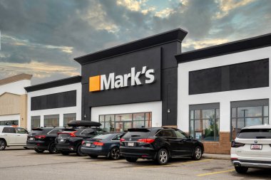 Calgary, Alberta, Kanada. 25 Temmuz 2025. Mark 'ın amblemi, park halindeki müşteri araçları ve çarpıcı bulutlu gökyüzü ile birlikte mağaza dışı, hareketli bir perakende ortamı simgeliyor..