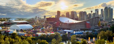 Calgary, Alberta, Kanada. 3 Ağustos 2025. Günbatımında Calgary Stampede, şehrin ufuk çizgisini, Saddledome 'u ve dönme dolaba sahip canlı panayırları gösteriyor..