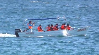 Cabo, Baja California Sur, Meksika. 10 Ağustos 2025. Küçük bir teknenin dinamik, düşük açılı bir görüntüsü. Can yelekli bir grup insan dalgalı mavi okyanus suyunda seyahat ediyor..