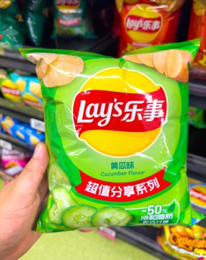 Calgary, Alberta, Kanada. 19 Ağustos 2025. Bir kişi, Lay 'in salatalık aromalı patates cipslerinden oluşan eşsiz bir poşet tutuyor. Uluslararası bir atıştırmalık ve küresel çeşitlilikte çeşitli tatlar sunuyor..