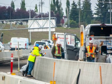 Calgary, Alberta, Kanada. 15 Ağustos 2025. Yol yapım işçileri bulutlu bir günde trafik aksamalarında otoyol bariyerlerini onarıyor.
