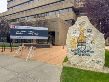 Calgary, Alberta, Kanada. 19 Ağustos 2025. Calgary 'deki Harry Hays Binası' nın detaylı ve düşük açılı bir görüntüsü. Üzerinde Kanada arması olan bir tabela ve yıpranmış bir kaya var..