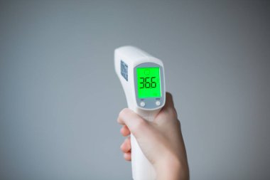 Ellerindeki dijital termometre 36.6 derece gösteriyor. Yüksek kalite fotoğraf