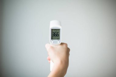 Ellerindeki dijital termometre 36.6 derece gösteriyor. Yüksek kalite fotoğraf