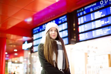 Kış Şapkalı Mutlu Kadın Arka planda Tren Gidiş Kurulu ile Gülümsüyor. Yüksek kalite fotoğraf