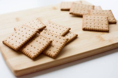 Ahşap bir tahtada sergilenen gevrek krakerler, rahat bir mutfak arka planına sahip. Yüksek kalite fotoğraf.