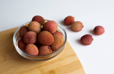  Mutfak ortamında tahta bir kesme tahtasına yerleştirilmiş taze liçi meyveleriyle dolu bir kase. Yüksek kalite fotoğraf.