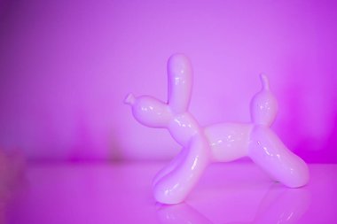  Yumuşak pembe neon ışıkla aydınlatılmış, modern ve sanatsal tasarım temaları için mükemmel balon köpek heykelciği. Yüksek kaliteli fotoğraf..