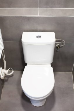 Çağdaş bir banyonun gri kiremitli duvarına yapıştırılmış temiz ve şık bir tuvalet. Minimalist iç mimari. Yüksek kaliteli fotoğraf..