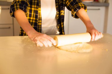 Pişirme sırasında hamuru merdaneyle düzleştiren bir çocuğun yakın çekimi. Yüksek kaliteli fotoğraf..
