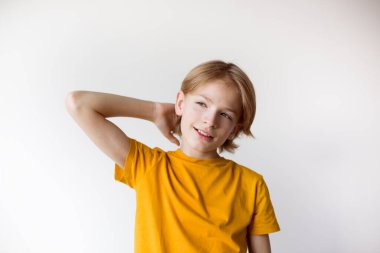 Neşeli bir çocuk, mutlu bir ifadeyle, beyaz bir arka planda, parlak bir gülümsemeyle doğrudan kameraya bakıyor. Yüksek kaliteli fotoğraf..