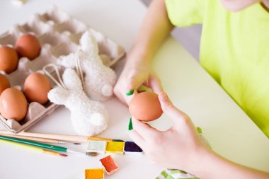 Renkli parmak boyaları kullanarak yumurtayı süsleyen çocuk ellerin yakın çekimi. Yaratıcılık kavramı, Paskalya hazırlığı ve çocukluk eğlencesi. Yüksek kaliteli fotoğraf..