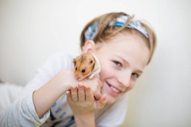 Gülümserken elinde bir hamster tutan mutlu bir çocuk. Çocukluk kavramı, evcil hayvan sevgisi ve mutluluk. Yüksek kaliteli fotoğraf..