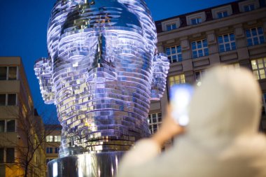 Prag 'da ünlü Franz Kafka heykelinin akıllı telefonuyla fotoğrafını çeken bir turist. Popüler dönüm noktası ve modern sanat cazibesi. Yüksek kaliteli fotoğraf..