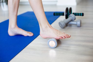 Ayak egzersizi için dokulu masaj silindirine baskı yapan bir ayak. Rehabilitasyon, fitness ve kişisel bakım kavramı. Yüksek kaliteli fotoğraf..