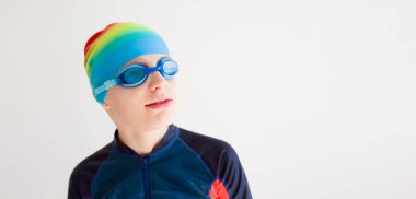 Beyaz arka planda duran yüzme kıyafeti giymiş sportif bir çocuk. Aktif çocukluk, yüzme ve zindelik kavramı. Yüksek kaliteli fotoğraf..