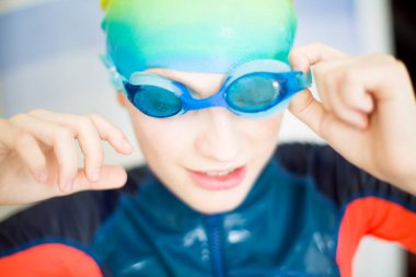 Sudan yeni çıkmış neşeli bir çocuk, başarılı bir yüzmeden sonra gülümsüyor. Çocuklar için eğlence, spor ve sağlıklı yaşam tarzı kavramı. Yüksek kaliteli fotoğraf..