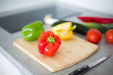 Tahta bir kesme tahtasının üzerinde bıçakla ikiye kesilmiş taze kırmızı bir dolma biber. Sağlıklı beslenme, yemek hazırlama ve organik sebze kavramı. Yüksek kaliteli fotoğraf..
