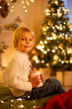 Tatlı çocuk, oğlum, Noel için süslü bir odada sarı bir koltukta oturuyor, rahat bir yer.