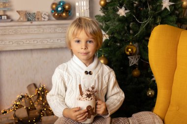 Tatlı çocuk, oğlum, Noel için süslü bir odada sarı bir koltukta oturuyor, rahat bir yer.