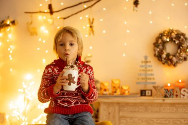 Tatlı çocuk, oğlum, Noel için süslü bir odada sarı bir koltukta oturuyor, rahat bir yer.