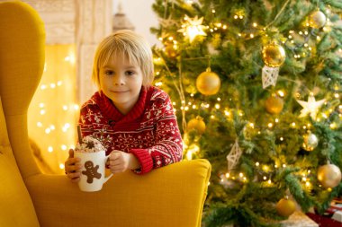 Tatlı çocuk, oğlum, Noel için süslü bir odada sarı bir koltukta oturuyor, rahat bir yer.