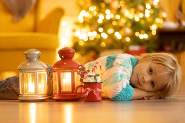 Tatlı çocuk, oğlum, Noel için süslü bir odada sarı bir koltukta oturuyor, rahat bir yer.