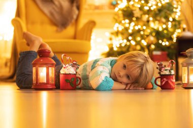 Tatlı çocuk, oğlum, Noel için süslü bir odada sarı bir koltukta oturuyor, rahat bir yer.