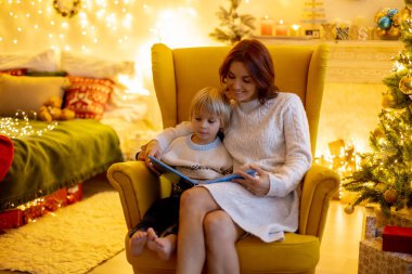 Tatlı çocuk, oğlum, Noel için süslü bir odada sarı bir koltukta oturuyor, rahat bir yer.