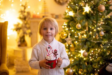 Tatlı çocuk, oğlum, Noel için süslü bir odada sarı bir koltukta oturuyor, rahat bir yer.