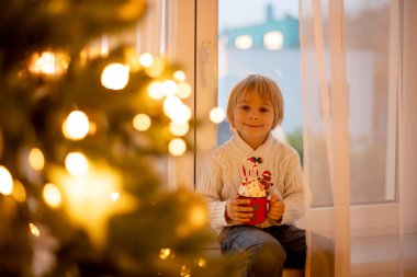 Tatlı çocuk, oğlum, Noel için süslü bir odada sarı bir koltukta oturuyor, rahat bir yer.