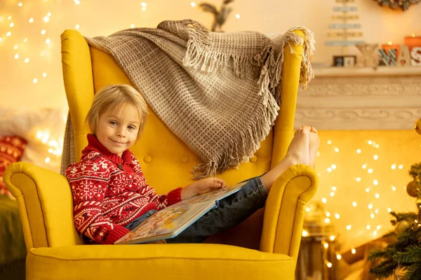 Tatlı çocuk, oğlum, Noel için süslü bir odada sarı bir koltukta oturuyor, rahat bir yer.
