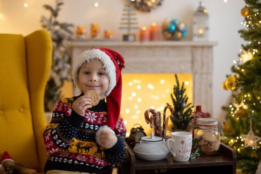 Tatlı çocuk, çocuk, Noel için dekore edilmiş odada oynuyor, evde süt içiyor ve kurabiye yiyor.