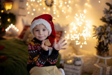 Tatlı çocuk, çocuk, Noel için dekore edilmiş odada oynuyor, evde süt içiyor ve kurabiye yiyor.